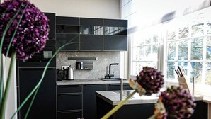 Una cocina moderna con armarios negros, encimera de mármol y ventana que proporciona luz natural.