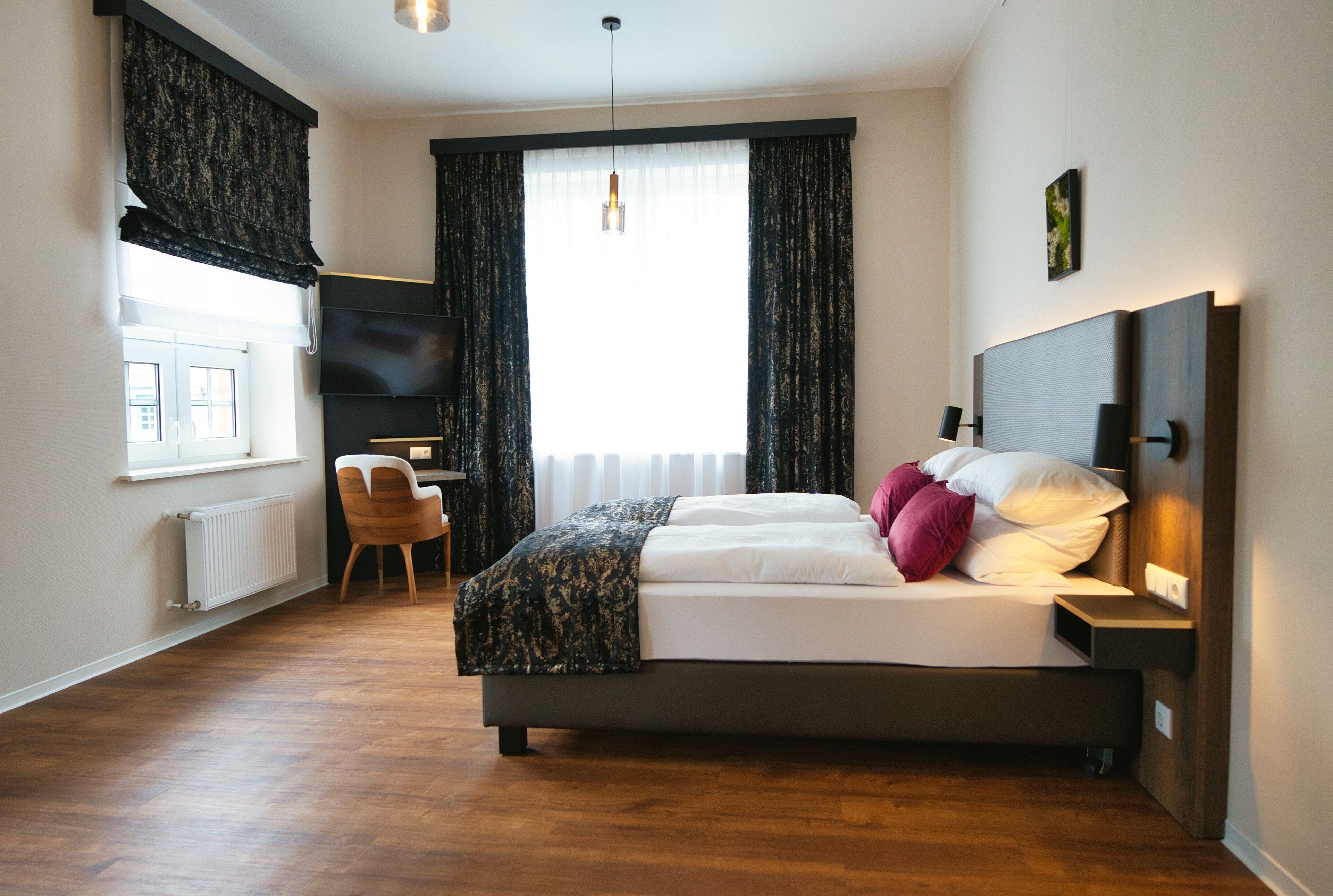A modern bedroom with a large bed, a desk, and a TV.