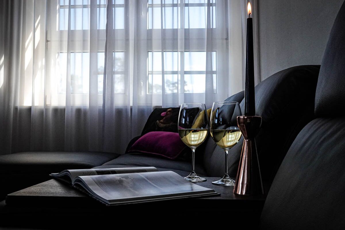A cozy room with a sofa, a table with a book and glasses, and a candle.