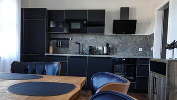 A modern kitchen with dark cabinetry, a wooden dining table, and blue chairs.