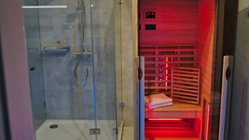 Un sauna doté d’une paroi en verre, d’un banc en bois et d’un écran numérique indiquant la température.