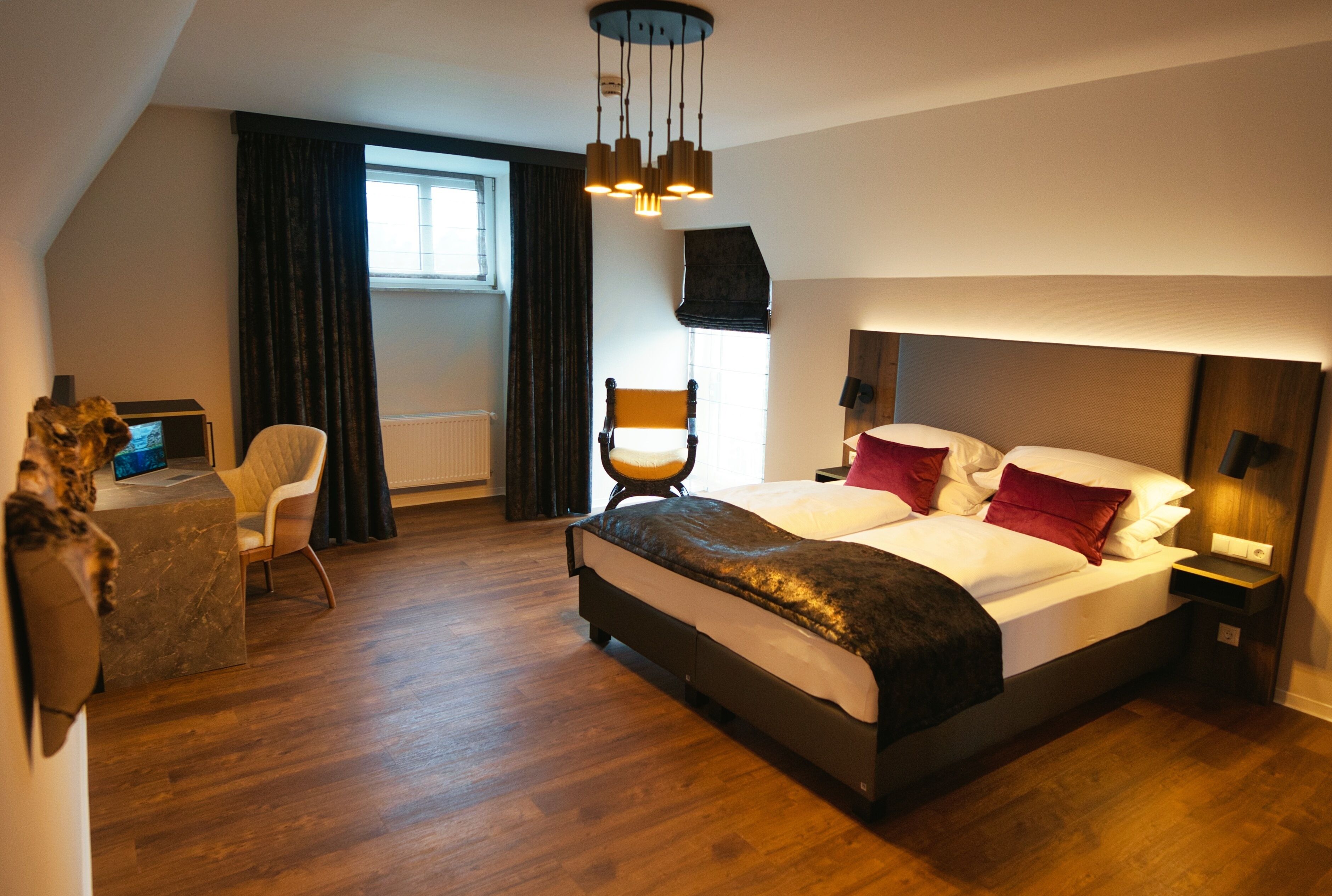 A modern hotel room with a large bed, a desk, and a chair.