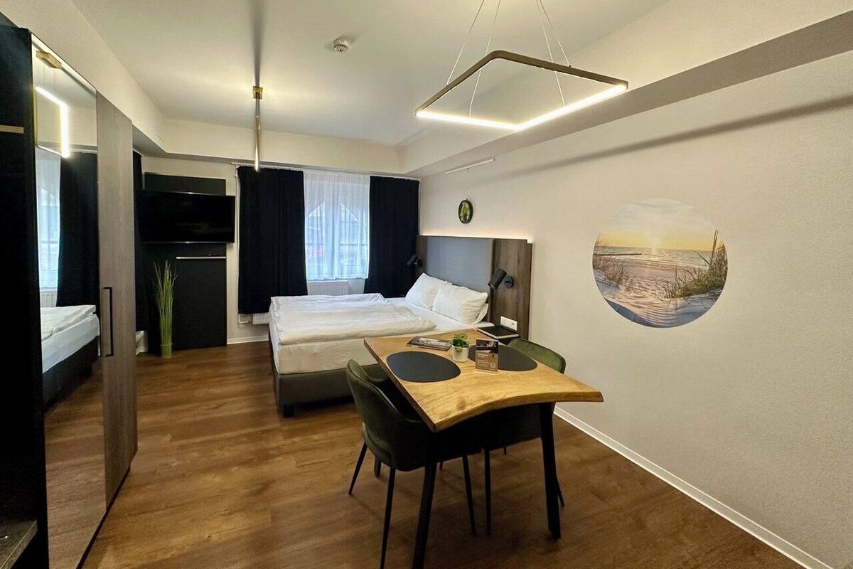 A compact hotel room with a bed, a desk, and a dining area.