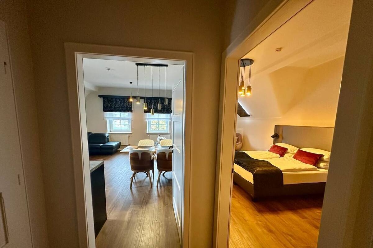 A modern apartment with a dining area, a bedroom, and a kitchen.