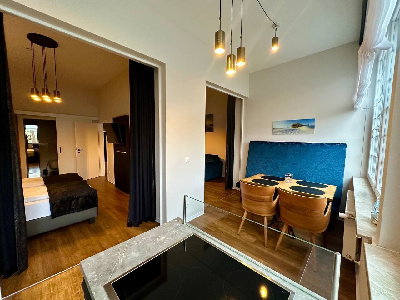 Ein modernes Wohnzimmer mit einem Glastisch, Holzboden und einem Essbereich mit blauer Akzentwand.