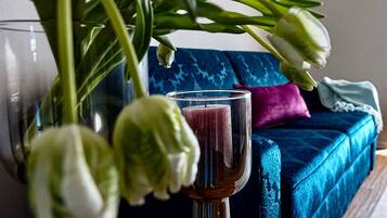 Ein Glas rote Flüssigkeit auf einem Tisch, im Hintergrund ein blaues Sofa und eine Pflanze.