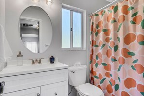 Un baño con un lavabo blanco, un espejo redondo y un inodoro.