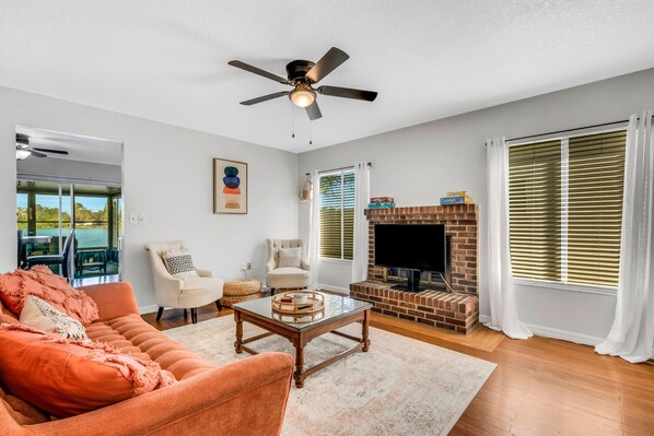 Una sala de estar con un sofá, sillones, una mesa de centro, chimenea y televisor.