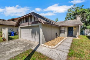 Una casa de un piso con garaje, un porche delantero y un pequeño jardín frontal.
