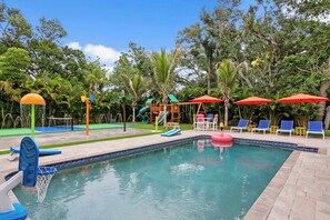 Ein Schwimmbecken mit Rutsche, Liegestühlen und Sonnenschirmen.