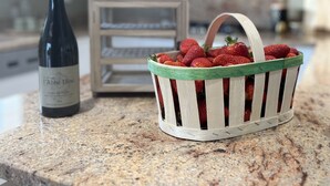 A kitchen counter with a wine bottle and a basket of strawberries. - Provencal house with heated pool and garden - sleeps 6 (Saint-Didier)