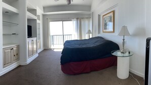A bedroom with a bed, a TV, a lamp, and a window with curtains. - Beachfront Penthouse in downtown Rosarito Beach (Rosarito)