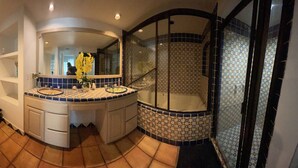 A bathroom with a toilet, sink, mirror, and shower area. - Beachfront Penthouse in downtown Rosarito Beach (Rosarito)