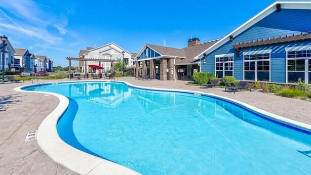 A swimming pool surrounded by modern houses with a clear blue sky. - An Exquisite 3 Rooms Townhome in Zionsville Suitable for Long-Term Stays (Zionsville)