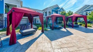 A patio area with red canopies, outdoor seating, and a stone floor. - An Exquisite 3 Rooms Townhome in Zionsville Suitable for Long-Term Stays (Zionsville)