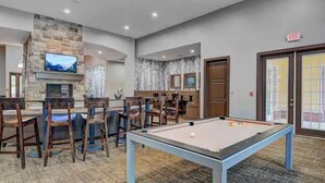 A pool table in a room with a stone fireplace, a television, and a bar area. - An Exquisite 3 Rooms Townhome in Zionsville Suitable for Long-Term Stays (Zionsville)