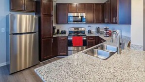 A modern kitchen with dark wood cabinets, stainless steel appliances, granite countertops, and a double sink. - An Exquisite 3 Rooms Townhome in Zionsville Suitable for Long-Term Stays (Zionsville)