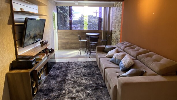 A modern living room with a flat-screen TV, a sofa, a coffee table, and a rug. - AconchegoF (Goiânia)