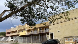A multi-story building with balconies, a parked car, and construction fencing. - AconchegoF (Goiânia)