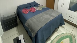A bedroom with a bed, a wardrobe, a nightstand, and a mirror. - AconchegoF (Goiânia)