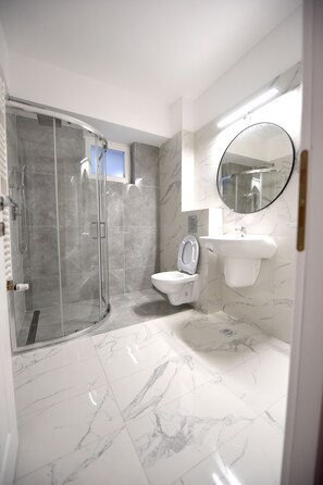 Enjoy a refreshing shower in the bathroom, featuring a glass-enclosed shower, toilet, and pedestal sink.