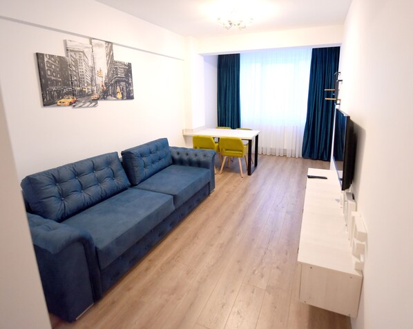 Relax in this stylish living space with a sofa, dining table, and flat-screen TV.