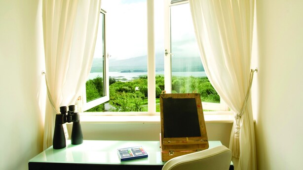 A room with a desk, a blackboard, and a view of a green landscape through a window. - Ring of Kerry Holiday Cottages (Greenane)