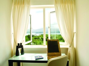 A room with a desk, a blackboard, and a view of a green landscape through a window. - Ring of Kerry Holiday Cottages (Greenane)