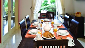 A dining area with a table set for breakfast, including plates, cups, and a fruit bowl. - Ring of Kerry Holiday Cottages (Greenane)