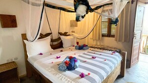 Ein Bett mit gestreifter Bettdecke, gerollten Handtüchern und Blütenblättern.