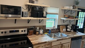 Eine moderne Küche mit Holzausstattung, einem Edelstahlspülbecken und einem eingebauten Ofen.