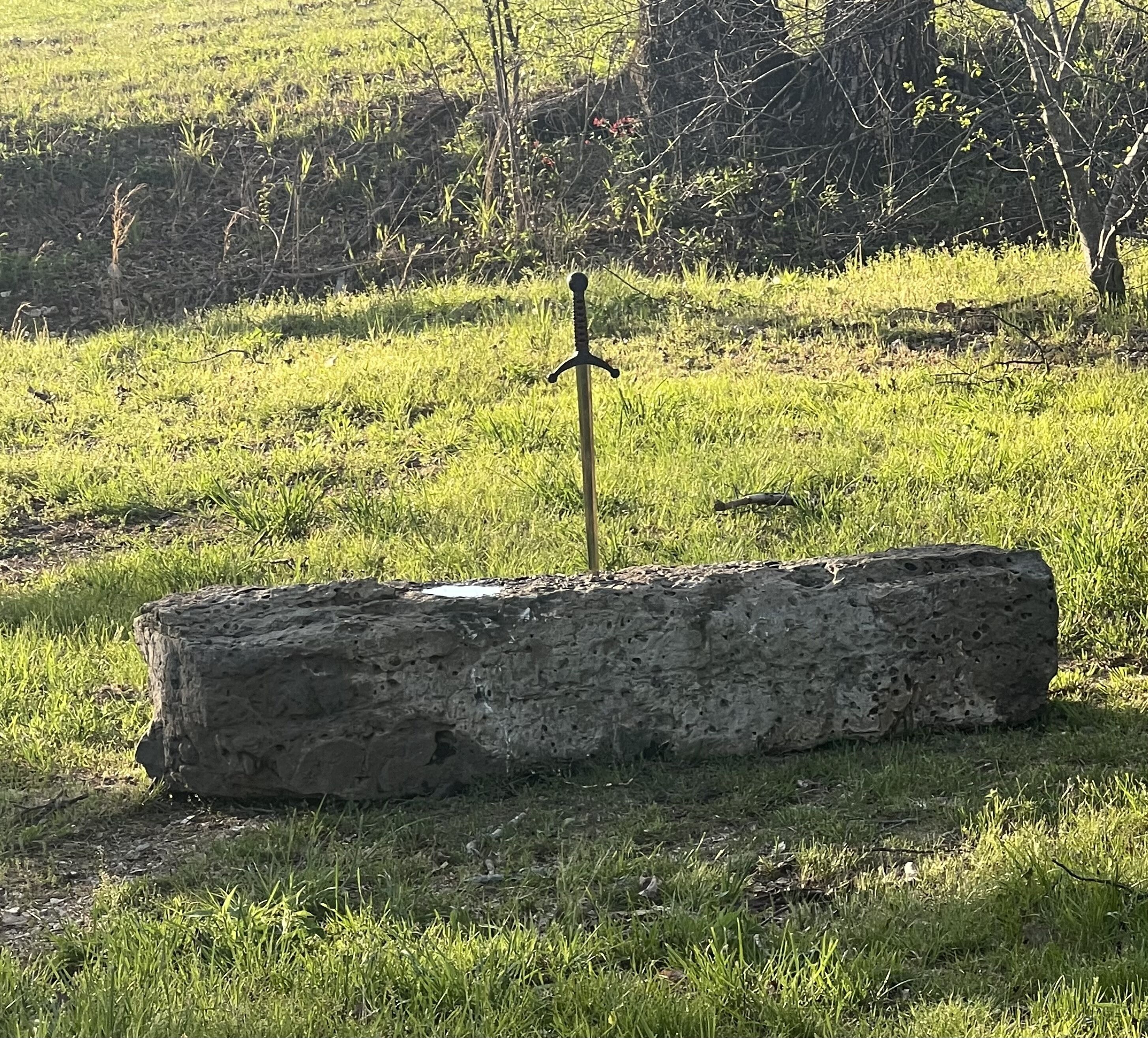 A stone slab with a metal cross in a grassy field.