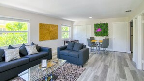 A modern living room with two sofas, a coffee table, and a dining area with a table and chairs. - Beach Condo | Hot Tub | Kitchen | Pet-Friendly (West Palm Beach)