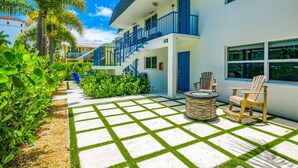 A hotel with a covered outdoor area featuring a fire pit and two Adirondack chairs. - Beach Condo | Hot Tub | Kitchen | Pet-Friendly (West Palm Beach)