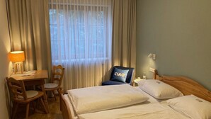 Una habitación de hotel con dos camas, un escritorio y una silla.