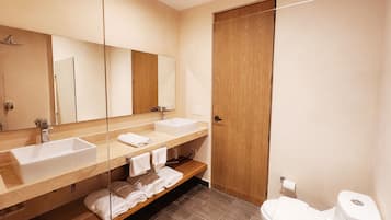 Un baño moderno con dos lavamanos, un espejo grande, una puerta de madera y un inodoro.
