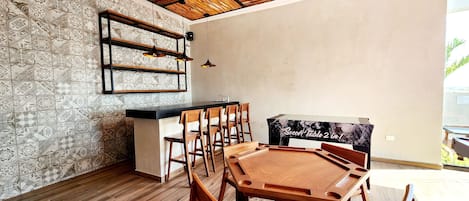 A dining area with a wooden table and chairs, a black countertop, and a patterned wall.