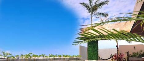 A pool area with clear blue water, a lounge chair, and a palm tree.