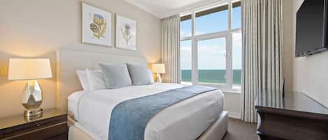 Une chambre d’hôtel avec un grand lit, deux tables de chevet avec des lampes, un téléviseur à écran plat et une fenêtre avec des rideaux.