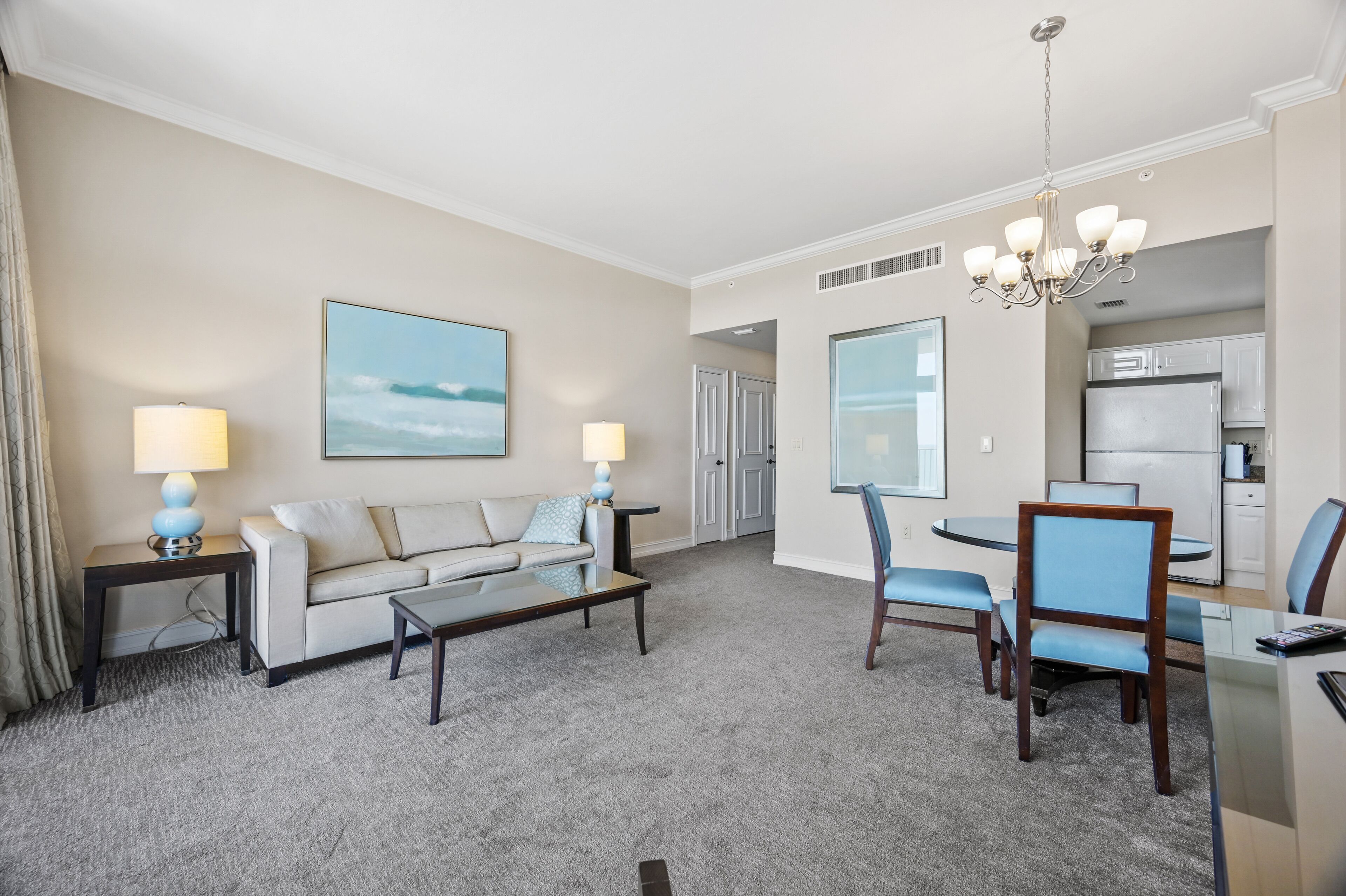 A hotel room with a living area, dining table, and kitchenette.