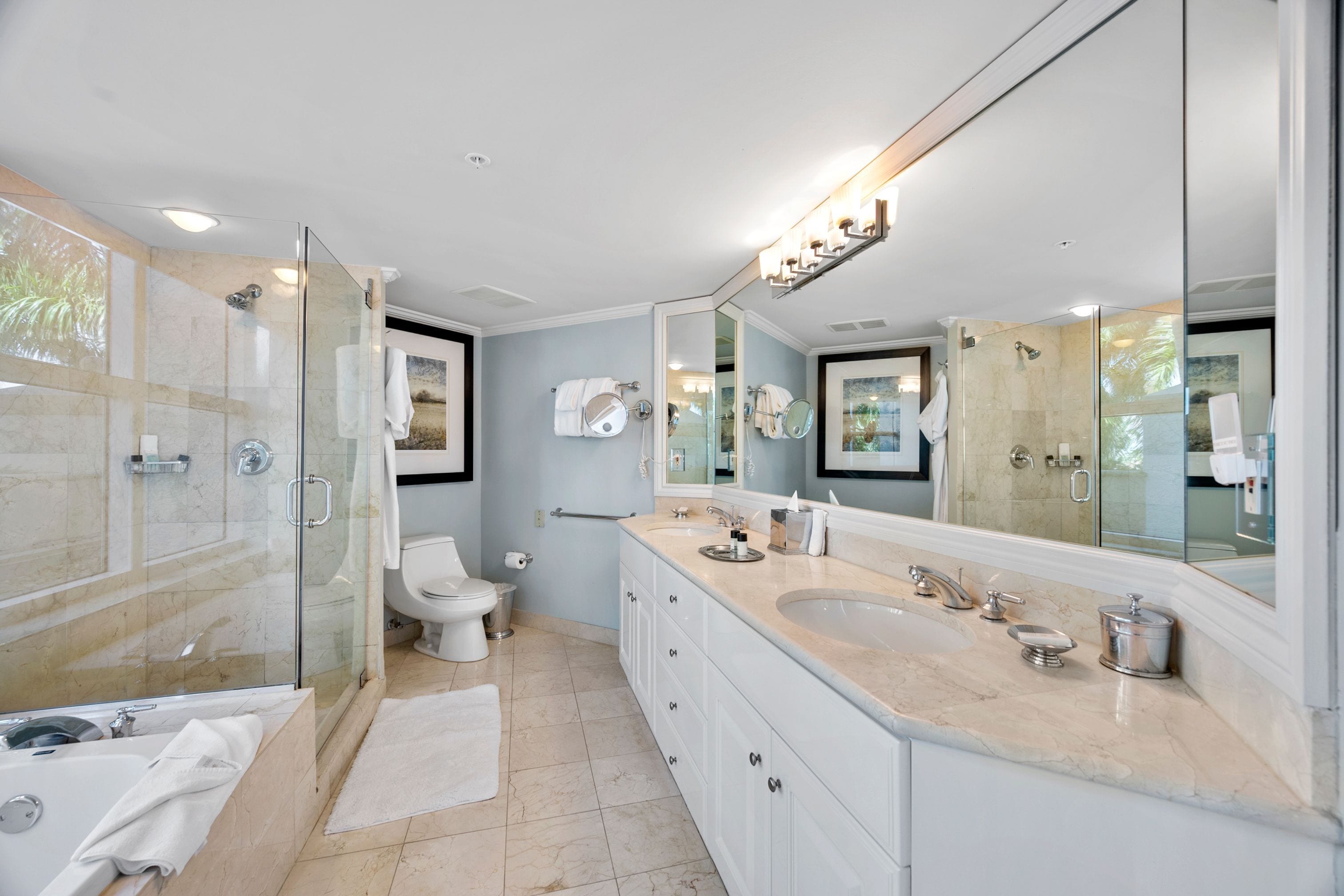 A modern bathroom with a glass-enclosed shower, a large vanity with a sink and mirror, and a toilet.
