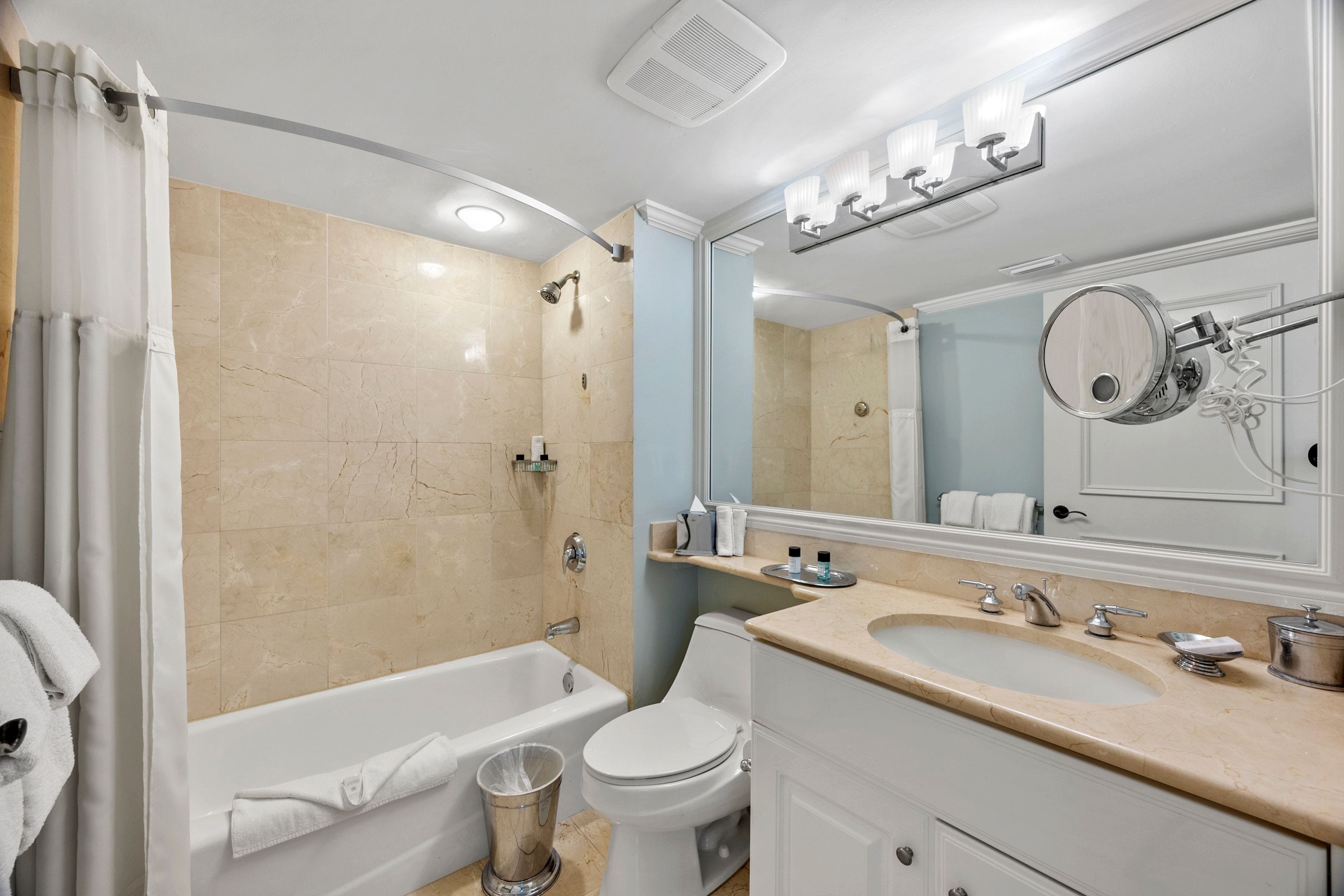 A modern bathroom with a bathtub, toilet, sink, and a large mirror.
