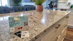 Une cuisine dotée d’un plan de travail en granit, d’une plante en pot et d’un code QR permettant de réserver.