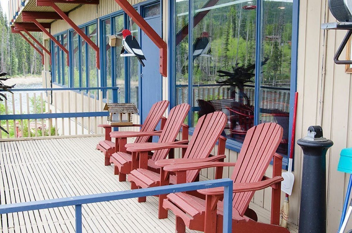 Eine Holzterrasse mit roten Adirondack-Stühlen, einem Holztisch und einem Vogelhaus.