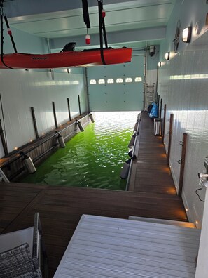 Une piscine avec une terrasse en bois, un kayak rouge et une échelle.
