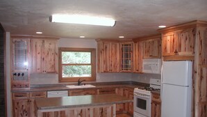 Una cocina con armarios de madera, una isla central, un fregadero, una estufa y un refrigerador.