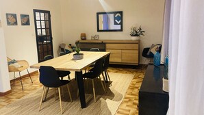 Un comedor con mesa de madera, sillas negras, alfombra tejida y una planta en maceta.