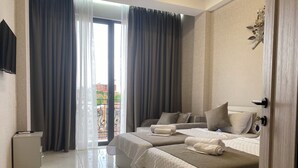 A hotel room with two beds, a TV, and a balcony with curtains. - Mimino T&G (Tbilisi)