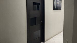 Un pasillo con una puerta moderna y una obra enmarcada en la pared.
