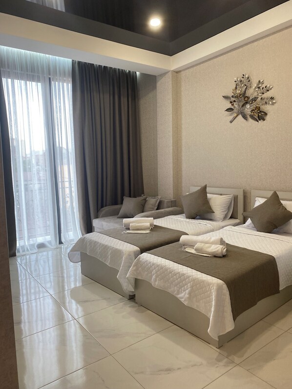 A modern hotel room with two beds, a large window with curtains, and a decorative wall piece. - Mimino T&G (Tbilisi)